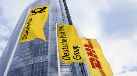 DHL expands green fleet with electric delivery vans DHL company logo on three yellow flags outside a tall company office building