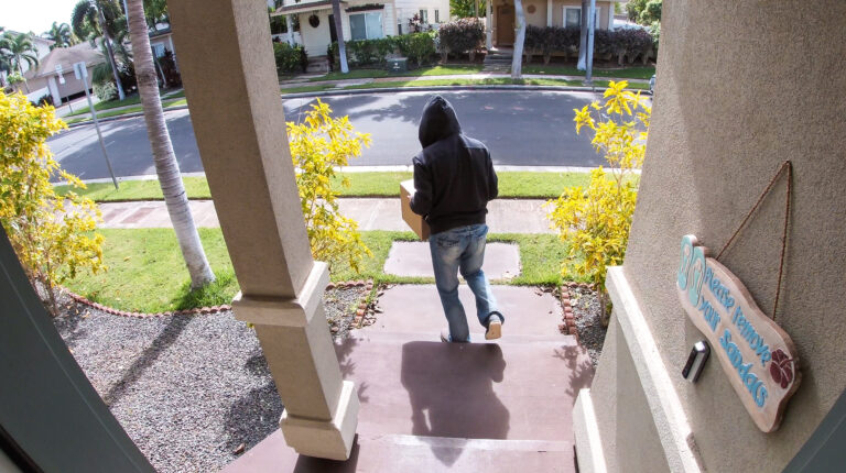 Person stealing delivery package from porch steps, surveillance