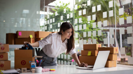 Female entrepreneur checks online orders to prepare to pack the boxes