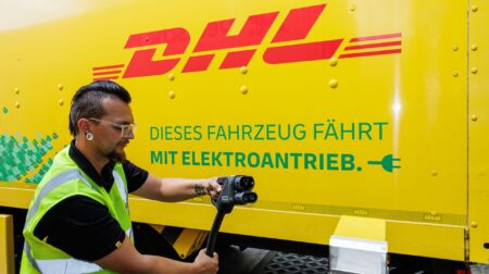 E.ON to provide charging infrastructure for DHL electric trucks Man plugging in electric charging to DHL branded van.