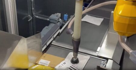 Robot arms handling mail items in conveyor belt