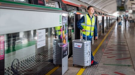 SingPost worker getting off train with suitcase of postal items