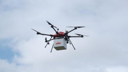 Drone in sky carrying Royal Mail parcel