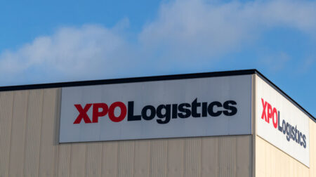 Red and black XPO Logistics logo on white background on warehouse