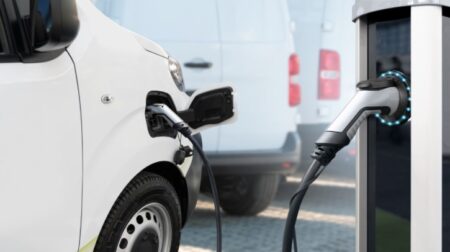 Logistics UK announces dates for electric vehicle training courses Electric delivery van with electric vehicles charging station.