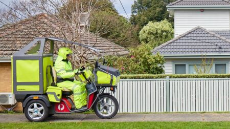 Australia Post employees agree pay rise terms Australia Post posal worker in high vis outfit on a electric delivery vehicle in suburban setting