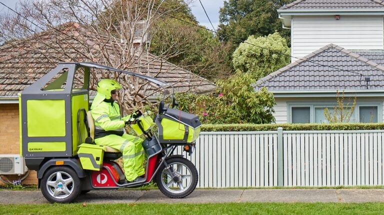 Australia Post posal worker in high vis outfit on a electric delivery vehicle in suburban setting