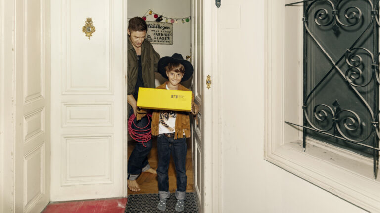 Young boy holding yellow Austrian Post parcel