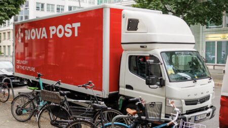 Red and white Nova Post van on street in Netherlands next to bicycles.