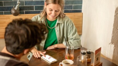 Woman looking at bpost app on her mobile phone while at cafe with man