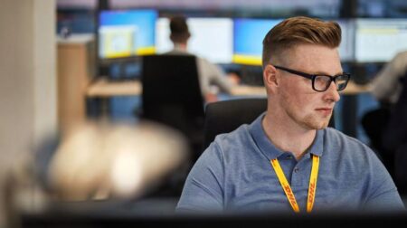 Man with DHL lanyard using computer