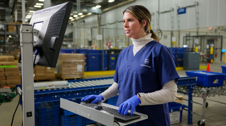 UPS expands healthcare logistics network with specialized cross-dock facilities Female UPS Healthcare worker at computer station