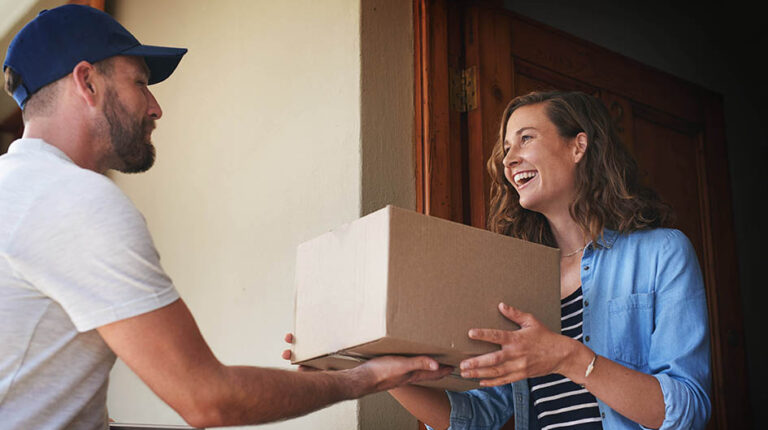 Last-mile delivery costs rise for 84% of businesses in UK and Europe, DS Smith reports Happy woman, delivery man and package box at door for order, parcel or cargo of customer in transport service. Female person receiving shipment from male courier, supply chain or deliver at the house