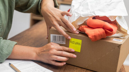 woman online shopper affixes a barcode sticker to a cardboard box, marking it for return and refund.