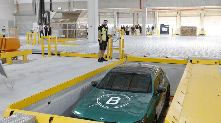 The DHL Global Forwarding air freight hub at Frankfurt Airport, with a car being packed into a container for transportation.