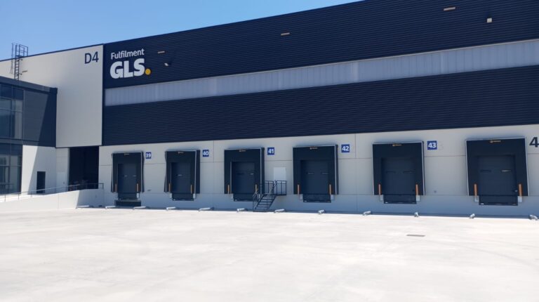 The exterior or the new GLS Spain fulfilment solutions facility in Torrejón de Ardoz in Madrid, with a row of docking stations and a blue sky.