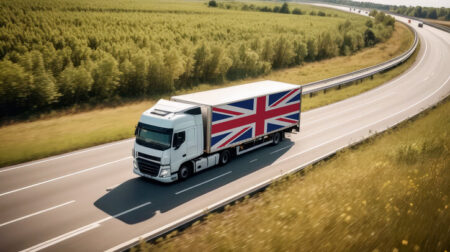 A Union Jack-flagged truck hauls cargo along the highway, embodying the essence of logistics and transportation in the UK.