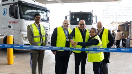 Staff in hihgh-vis yellow jackets cut the ribbon at the opening of a new Hellmann Worldwide Logistics contract logistics center in Truganina, Victoria, Australia.
