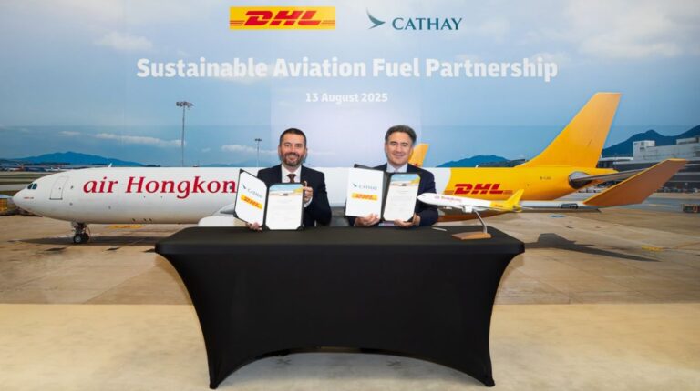 Peter Bardens, senior vice president for network operations and aviation, Asia-Pacific, DHL Express, and Tom Owen, director – cargo, Cathay Group (right) sit at a table holding the signed agreement in front of a board of company logos and a DHL-branded jet