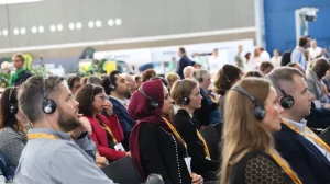Parcel+Post Expo attendees listen to a presentation on the show floor