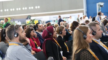 Parcel+Post Expo attendees listen to a presentation on the show floor