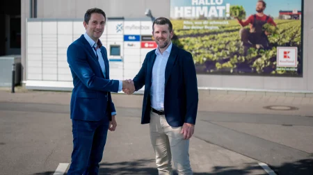 Jonathan Grothaus, CEO and founder of Myflexbox (left), with René Wolf, managing director of leasing and commercial facility management at Kaufland, shake hands outside a Kaufland supermarket store in Germany