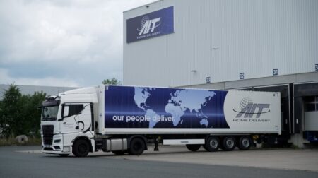 An AIT Home Delivery-branded truck parked at a depot