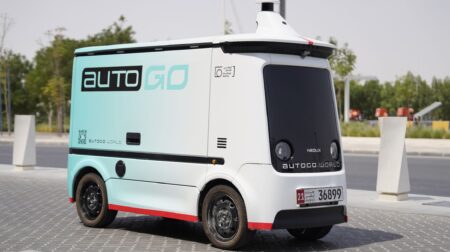An AutoGo autonomous delivery vehicle drives down a quiet urban street