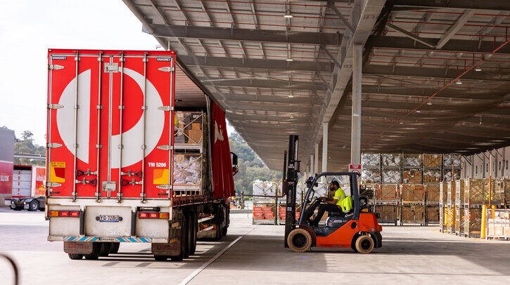 Australia Post to open multimillion-dollar parcel facility in Queensland An Australia Post delviery truck parked at a sorting facility with a forklift loading cargo