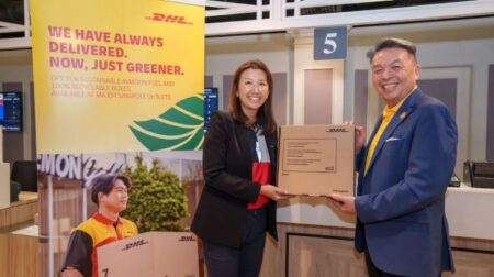 DHL and SingPost partner on accessible and sustainable shipping services Representatives of DHL and SingPost hold a cardboard box in front of a board with the company logos to mark the announcement of a new partnership to deliver accessible and sustainable shipping services across Singapore