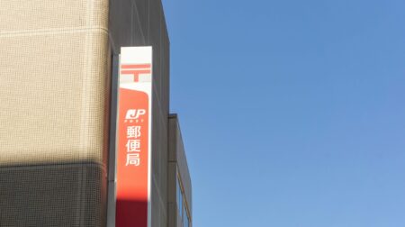 The Japan Post logo on the outside of a building with a clear blue sky