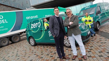 An Post head of sustainability Owen Keogh and An Post CEO David McRemond stand in front of a green electric delivery van and electric truck