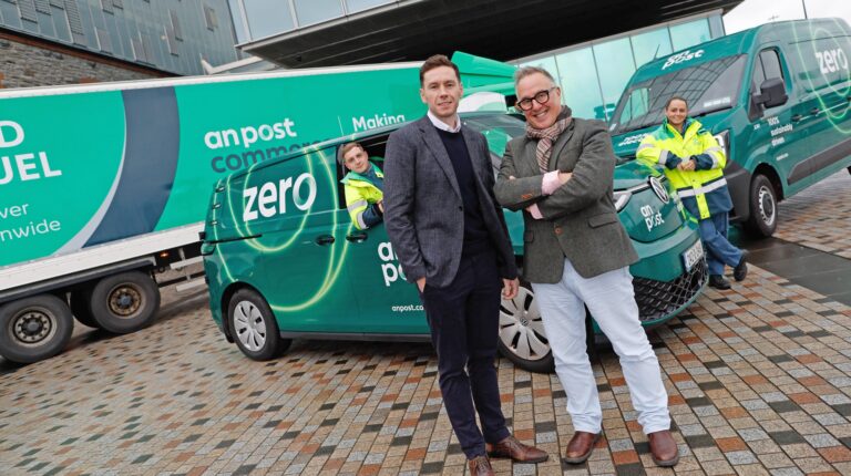 An Post head of sustainability Owen Keogh and An Post CEO David McRemond stand in front of a green electric delivery van and electric truck