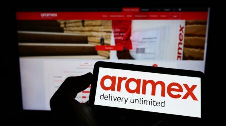 A person holds a tablet with Aramex logo on