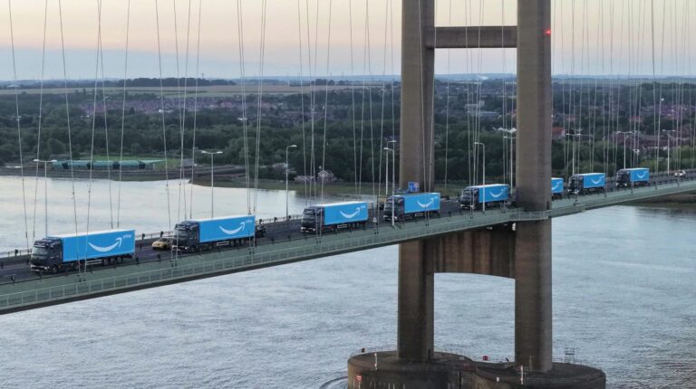 Amazon accelerates UK fleet electrification with record eHGV rollout Blue Amazon trucks drive over a bridge in the UK