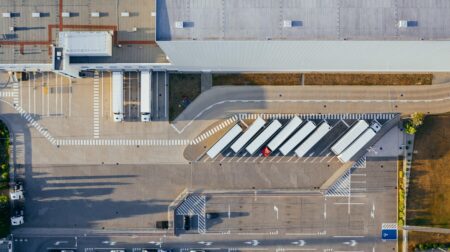 Aerial view of a logistics warehouse, with trucks parked outside in loading bays