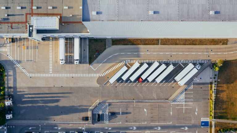 Aerial view of a logistics warehouse, with trucks parked outside in loading bays