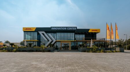 The expanded DHL Innovation Center in Dubai, with company flags on the right-hand side and the company branding and name across the top of the frontage