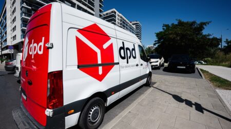 Geopost reports 5% volume growth in 2025 amid margin pressure A white Geopost delivery van with company branding in red parked outside glass-fronted buildings. The sun is shining.