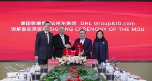 Tobias Meyer, CEO, DHL Group; Dongming Wu, CEO, DHL Express China; Eric Zheng, head of global service, Jingdong Logistics; Sandy Xu, CEO, JD.com. shake hands at the singing of an MOU in front of red JD.com branding.