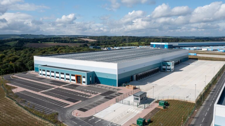 Aerial view of Evri's new £4m Barnsley fulfillment center. It has a grey roof and white and green sides. Green fields stretch out into the distance.