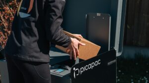 An Omniva delivery worker delivers a parcel to a Picapac private parcel locker.