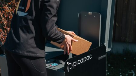An Omniva delivery worker delivers a parcel to a Picapac private parcel locker.
