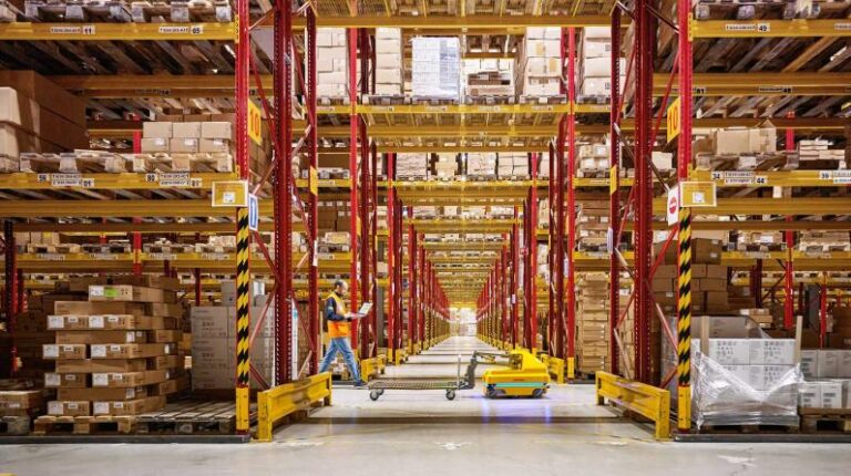 A DHL warehouse, with high stacks of shelving in yellow and red.