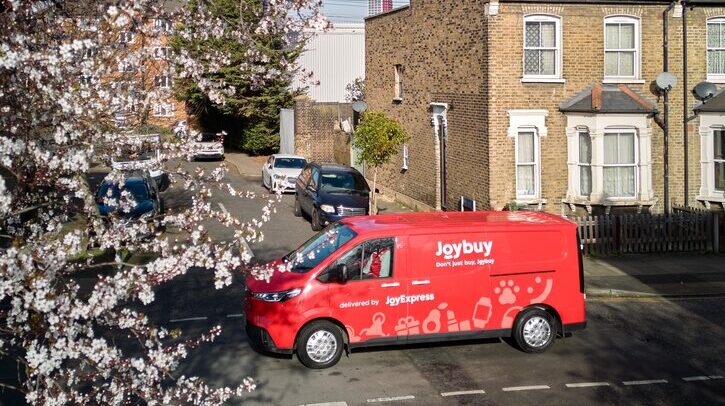 Red JoyExpress delivery van driving along UK residential street.