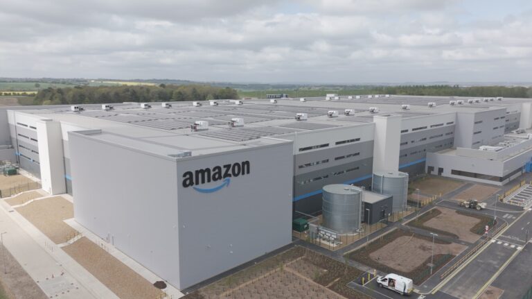 Amazon invests £1bn in two fulfilment centers in Northampton, UK A large fulfillment facility with Amazon written on the side.