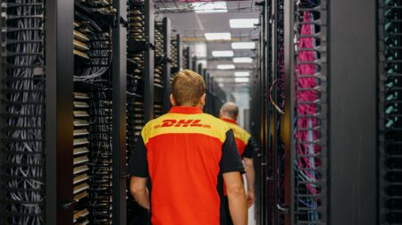 Two DHL colleagues walking down a corridor of server racks.