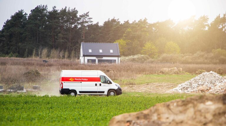 Poczta Polska launches tender for 5,500 mobile terminals A Poczta Polska delivery van drives through a rural environment. There is grass in the foreground and a small home in the distance.