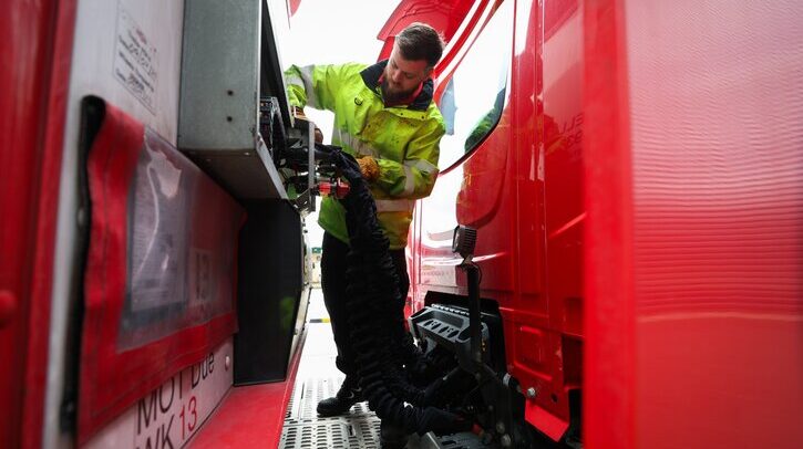 A Royal Mailer worker services an electric truck.