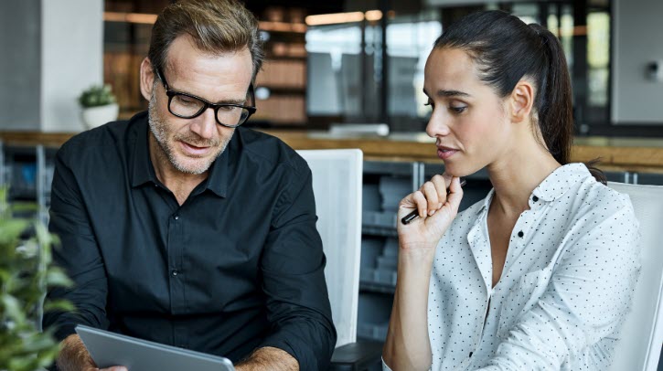 OPINION: Why digital communication still needs one recognized place for important messages A man and a woman look at a tablet in an office environment.